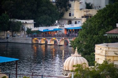 Eski kemer köprüsü Pichola Gölü 'nün üzerinden geçiyor. İnsanlar akşam karanlığında karşıya geçiyorlar.