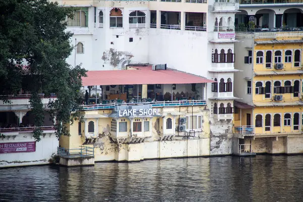 Geleneksel taş binalar, Udaipur 'daki Pichola Fateh Efsanesi' nin kıyısında su yollarında tekneleri olan restoranlar.