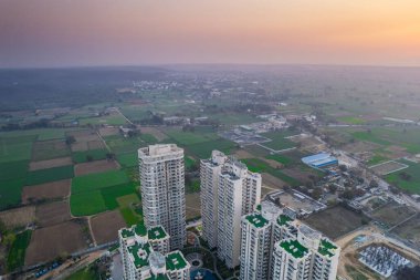 Havadan çekilen lüks, zengin, lüks binalar, ofis alışverişi için çevresi dağlarla çevrili yeşil tarlalar, doğanın ortasında yaşadığını gösteriyor.