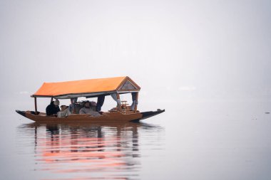 Srinagar, Kashmir - 3 Ocak 2025: Tahta Shikara teknelerinde oturan turistler ve ünlü dal gölü üzerindeki renkli çatılar popüler turistik aktiviteleri gösteriyor