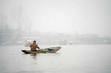 Yalnız kayıkçı, Dal Gölü 'nün sisli sularında tahta bir kanoda kürek çekiyor. Srinagar Kaşmir' deki bu popüler turizm beldesinin izolasyonunu gösteriyor.