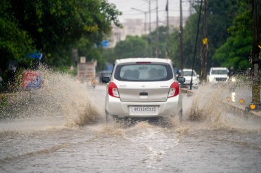 Gurgaon, Delhi, Hindistan - 1 Eylül 2025: Ana yollarda, bozuk yollarda, çukurlarda ve muson yağmurlarında her gün karşılaşılan derin suların her tarafına su sıçrayan küçük araba