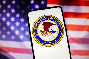 13 Kasım 2022, Brezilya. Bu resimde, ABD Adalet Bakanlığı (DOJ) logosu arka planda ABD bayrağı bulunan bir akıllı telefon ekranında sergilenmektedir.