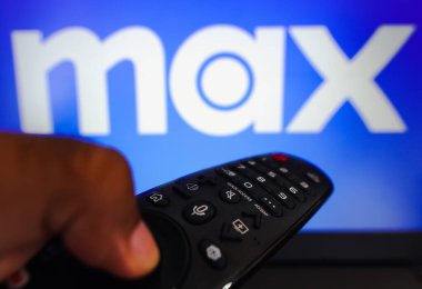 13 Nisan 2023, Brezilya. Bu resimde, TV ekranında Max logosu önünde uzaktan kumandayı tutan bir el var.