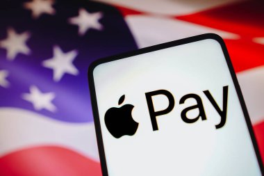 16 Mayıs 2023, Brezilya. Bu resimde, Apple Pay logosu akıllı telefon ekranında ve arka planda, Amerika Birleşik Devletleri bayrağı sergilenmektedir.