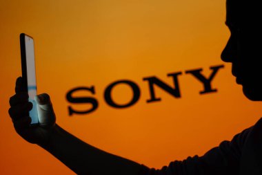 13 Haziran 2023, Brezilya. Bu resimde, Sony logosu arka planda cep telefonu tutan siluetli bir kadının görüntüsü var.