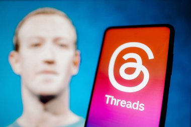 7 Temmuz 2023, Brezilya. Bu fotoğraf illüstrasyonunda, İplik logosu akıllı telefon ekranında gösteriliyor. Arka planda, sosyal ağın yaratıcısı Mark Zuckerberg 'in görüntüsü