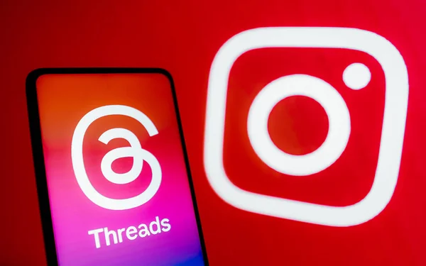 stock image July 7, 2023, Brazil. In this photo illustration, the Threads logo is displayed on a smartphone screen. In the background, the logo of the social network Instagram