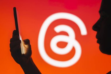 12 Temmuz 2023, Brezilya. Bu resimde, bir kadının siluetinde arka planda iplik logosu olan bir akıllı telefon var.