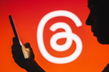12 Temmuz 2023, Brezilya. Bu resimde, bir kadının siluetinde arka planda iplik logosu olan bir akıllı telefon var.