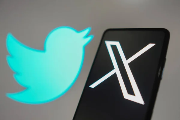 stock image July 24, 2023, Brazil. In this photo illustration, the Twitter (X) new logo seen displayed on a smartphone. In the background, the old bluebird social network logo