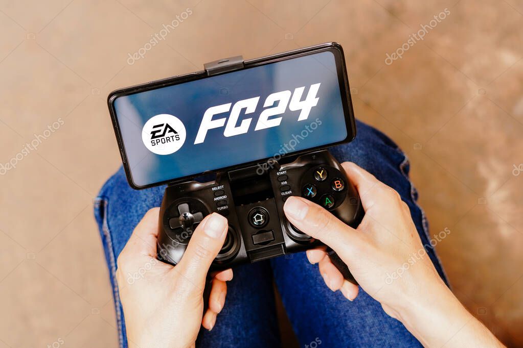 August 8, 2023, Brazil. In this photo illustration, a person playing on a joystick and the EA Sports FC 24 logo displayed on a smartphone screen