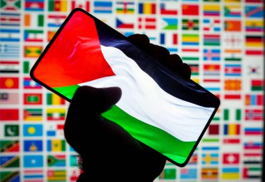 12 Ekim 2023, Brezilya. Bu resimde, Filistin bayrağı akıllı telefon ekranında ve arka planda birçok ülkenin bayrakları sergilenmektedir.