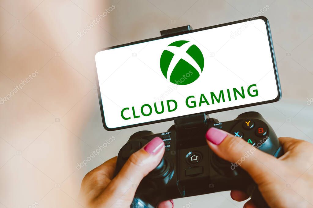 December 4, 2023, Brazil. In this photo illustration, the Xbox Cloud Gaming logo is displayed on a smartphone screen as a person plays on a gaming gamepad