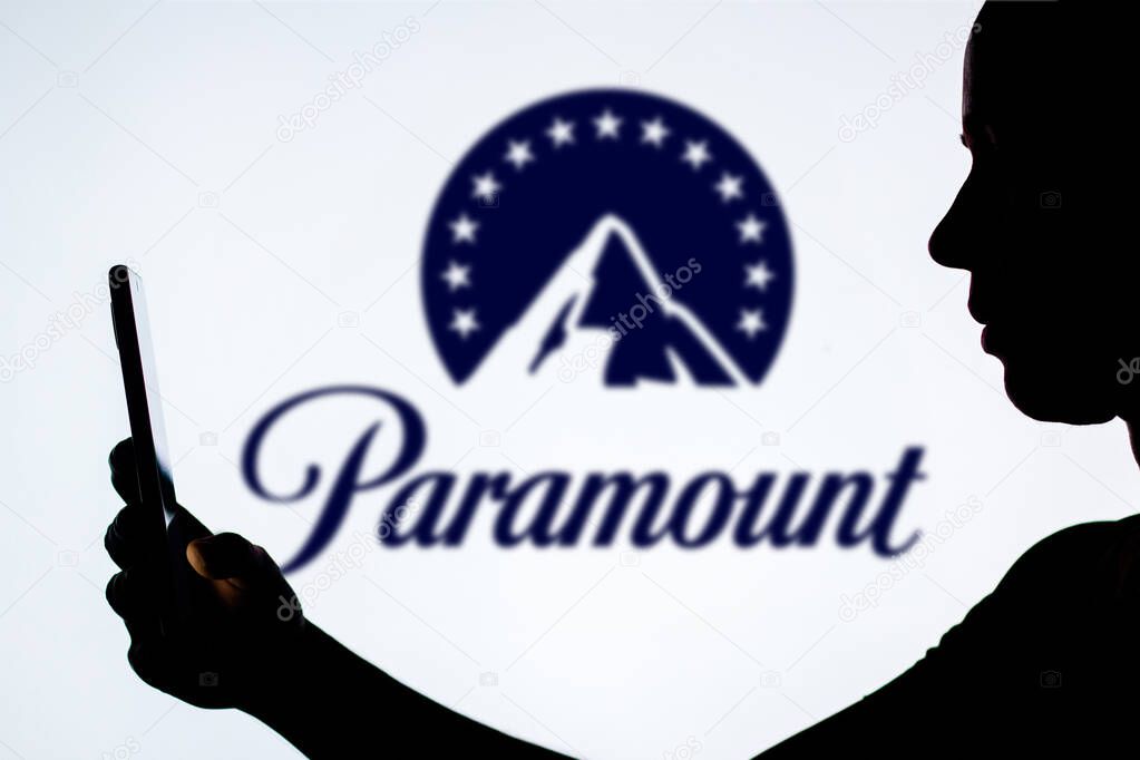 December 9, 2023, Brazil. In this photo illustration, a woman's silhouette holds a smartphone with the Paramount Global logo in the background