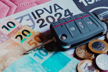12 Aralık 2023, Brezilya. Bu resimde ödeme fişi IPVA (Imposto ayık a Propriedade de Veculos Automotores) Brezilya 'nın gerçek para notları ve sikkelerinin yanında.