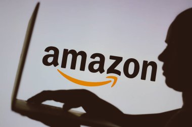 9 Ocak 2024, Brezilya. Bu resimde, Amazon logosu arka planda bir kişinin siluetinde bir defter kullanarak görülüyor.