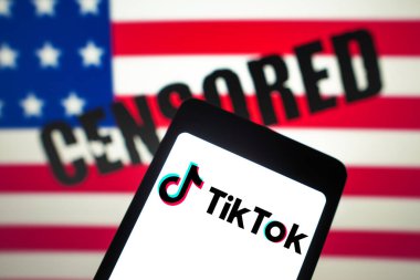 12 Mart 2024, Brezilya. Bu resimde, TikTok logosu akıllı telefon ekranında ve arka planda, sansürlenmiş metinlerle Amerika Birleşik Devletleri bayrağı (ABD) sergilenmektedir.