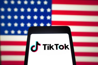 12 Mart 2024, Brezilya. Bu resimde, TikTok logosu akıllı telefon ekranında ve arka planda Amerika Birleşik Devletleri bayrağı (ABD) gösterilir.)