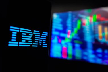 15 Mart 2024, Brezilya. Bu fotoğraf illüstrasyonunda, Uluslararası İş Makineleri Şirketi (IBM) logosu, arka planda borsanın grafik temsili ile akıllı telefon ekranında sergilenmektedir.