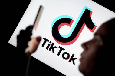 15 Mayıs 2024, Brezilya. Bu resimde, elinde akıllı telefon olan kadın ve TikTok logosu arka planda görülüyor.