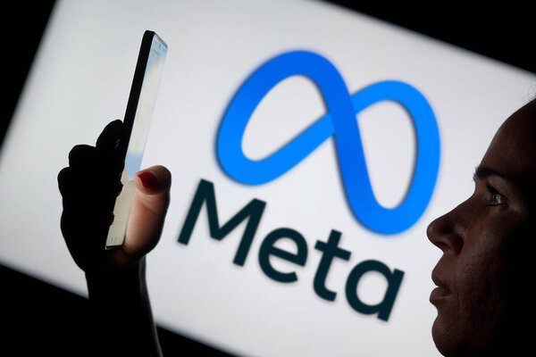 May 15, 2024, Brazil. In this photo illustration, the woman holding a smartphone and the Meta Platforms, Inc. logo is seen in the background