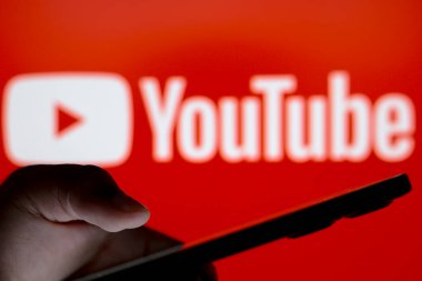 10 Temmuz 2024, Paraguay. Bu resimde, Youtube logosu, elinde akıllı telefon tutan siluet insanların arka planında görülüyor.