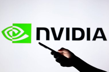 3 Ağustos 2024, Paraguay. Bu resimde, Nvidia Şirketi logosu arka planda siluet bir elle akıllı telefon tutarken görülüyor.