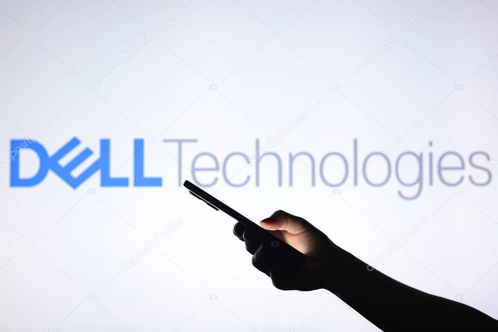 August 3, 2024, Paraguay. In this photo illustration, the Dell Technologies logo seen in the background with a silhouette hand holding a smartphone