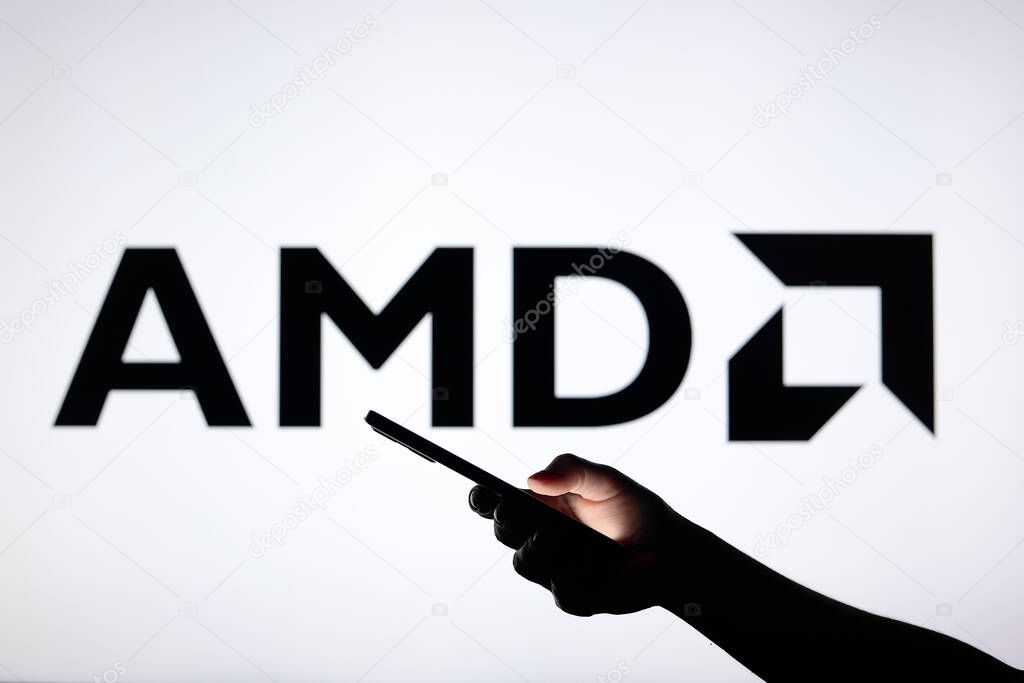 August 3, 2024, Paraguay. In this photo illustration, the Advanced Micro Devices, Inc. (AMD) logo seen in the background with a silhouette hand holding a smartphone