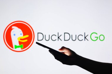 15 Ağustos 2024, Paraguay. Bu resimde, DuckDuckGo logosu arka planda siluet bir elle akıllı telefon tutarken görülüyor.