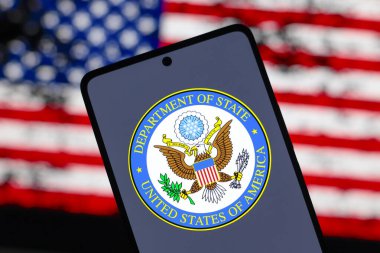 15 Ağustos 2024, Paraguay. Bu resimde, ABD Dışişleri Bakanlığı (DOS) logosu akıllı telefon ekranında ve arka planda Amerika Birleşik Devletleri bayrağı (ABD) gösterilir.)