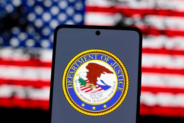 15 Ağustos 2024, Paraguay. Bu resimde, ABD Adalet Bakanlığı (DOJ) logosu akıllı telefon ekranında ve arka planda Amerika Birleşik Devletleri bayrağı (ABD) gösterilir.)