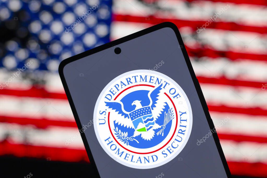 August 15, 2024, Paraguay. In this photo illustration, the United States Department of Homeland Security (DHS) logo is displayed on a smartphone screen and in the background the flag of the United States of America (USA)