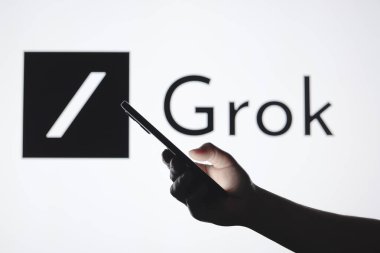 September 5, 2024, Paraguay. In this photo illustration, the Grok AI logo seen in the background with a silhouette hand holding a smartphone clipart