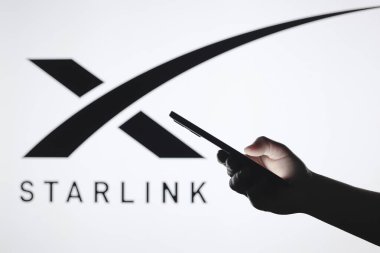 5 Eylül 2024, Paraguay. Bu resimde, arka planda akıllı telefonu tutan siluet bir el ile Starlink logosu görülüyor.
