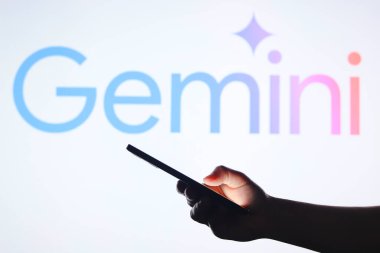 5 Eylül 2024, Paraguay. Bu resimde, Gemini logosu arka planda bir siluet elle akıllı telefon tutarken görülüyor..
