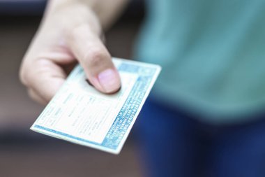 Man holds National Driver's License (CNH). Official document of Brazil, which attests the ability of a citizen to drive land vehicles clipart