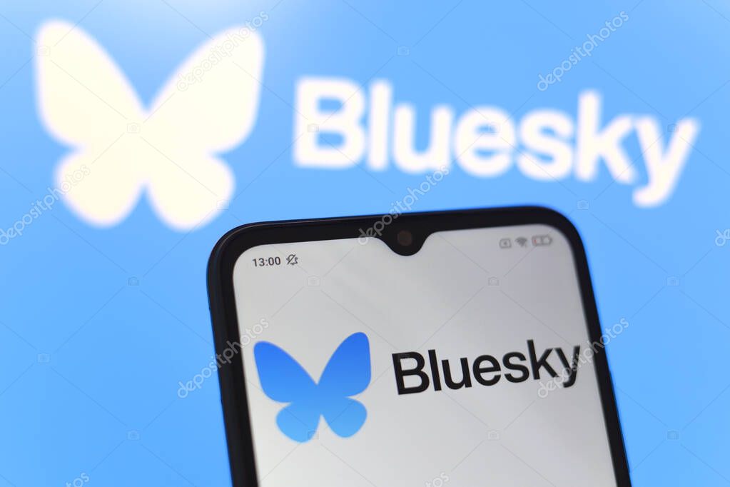 The logo of the social network Bluesky is displayed on the screen of a smartphone and on the computer screen in the background, in Reno, United States, on November 20, 2024