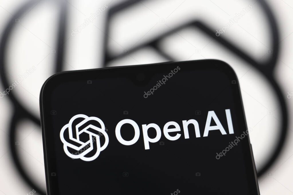 The OpenAI logo is displayed on a smartphone screen and in the background on a computer screen in Reno, United States, on November 21, 2024