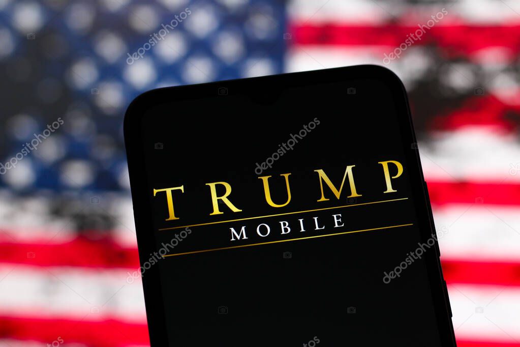 In this photo illustration, the Trump Mobile logo is seen displayed on a smartphone screen and in the background, the flag of the United States of America, June 17, 2025, United States