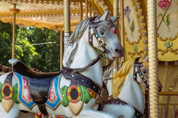 Old French carousel in a holiday park during sunny day. Horses on a traditional fairground vintage carousel. Merry-go-round with horses. Vintage carousel horse