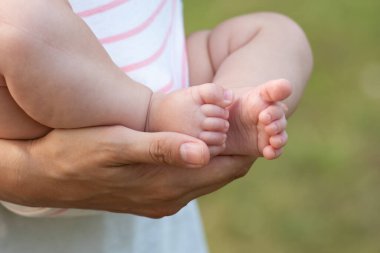 Değerli Başlangıçlar: Sevgi Ellerindeki Bebek Ayaklar. Anne Eller 'deki Bebek Ayaklar. Yeni doğmuş parmaklar White Soft arka planının üzerine kapanır. Annem Sevgiyle Minik Ayaklar 'ı tutuyor. Doğum ve Çocuk Bakımı Konsepti