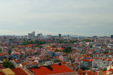 Lizbon, Portekiz 'in çarpıcı panoramik manzarası, güneşli bir günde ikonik kırmızı çatılarını, modern ve tarihi mimarisini ve canlı şehir manzarasını sergiliyor..