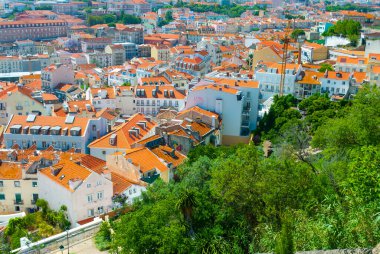 Lizbon, Portekiz 'in çarpıcı panoramik manzarası, güneşli bir günde ikonik kırmızı çatılarını, modern ve tarihi mimarisini ve canlı şehir manzarasını sergiliyor..