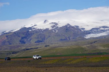 Dağlar karla kaplı ve İzlanda 'da araba sürüyor.