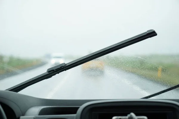 Driving a car in the rain with activated windshield wipers