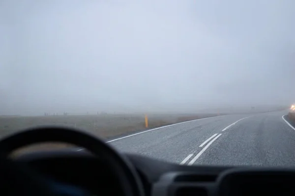 stock image Driving a car in fog - perspective of a driver