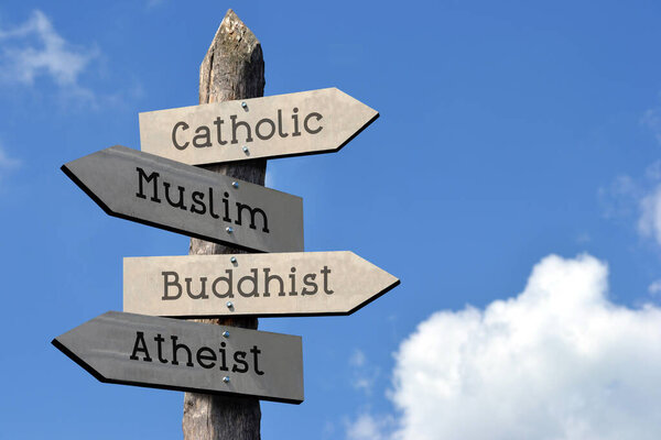 Catholic, Muslim, Buddhist, Atheist - wooden signpost with four arrows, sky with clouds