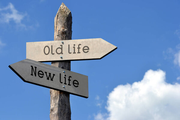 Old life and new life - wooden signpost with two arrows, sky with clouds